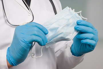 close up of doctor's hand in medical gloves with medical face mask for protection against infection