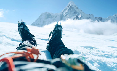 POV shoot of a high altitude mountain climber's lags in crampons. He lying and resting on snow ice...