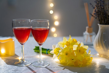 glasses red wine on table with bouquet daffodils