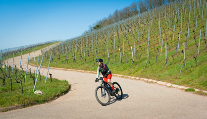 ageless happy senior woman riding her elechtric mountain bike on sunny springtime day in the Vineyards of the Bottwartal near Heilbronn, Germany