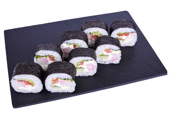 Traditional fresh japanese sushi futomaki on black stone Futomaki Snow Crab on a white background. Roll ingredients: surimi, philadelphia cheese, tomato, cucumber, lettuce, nori, rice.