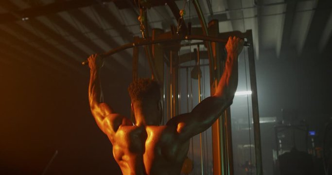 Man working out back muscles in dark gymMan working out in dark gym - Powered by Adobe