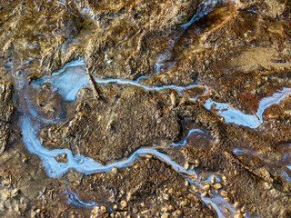 Hintergrund, Textur, Template: Rinnsale im Uferschlamm eines Sees mit Spiegelung des Himmels