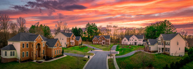 Neighborhood street sunset panorama of modern upper middle class single family houses American real estate in a new construction in Maryland USA colorful dramatic sky