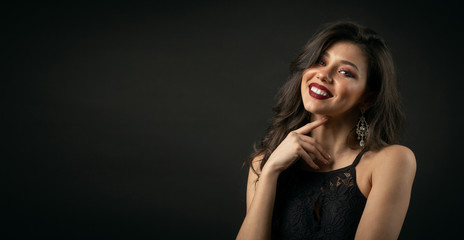 Fototapeta premium Half-body portrait of luxurious-looking lady with bright make-up touching neck over black background with copyspace