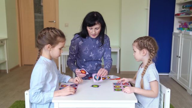 teacher with children play cards geometric shapes