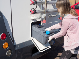 A lady motorhome owner removes a cassette toilet from her motorhome to empty it.She wears...