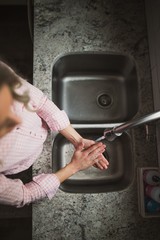 Young woman washing her hands at the kitchen sink