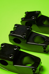 Three stem for bmx steering lie on a bright green background. Parts for bicycles. Extreme sports.