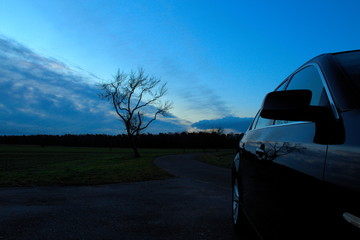 Auto vor Sonnenaufgang, blauer Himmel, Spiegelungen im Lack