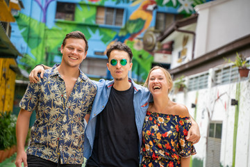 three people embraced by the shoulder dressed in colorful summer clothes in the middle of the street