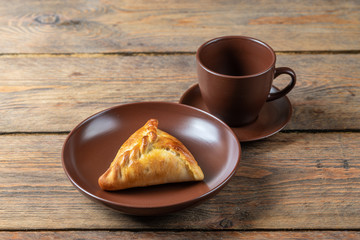plate with fresh hot mini pie and coffee cup on wooden table, close view 