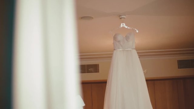 Beautiful tender wedding dress is hanging on the ceiling in the room, wedding preparation, bridal details
