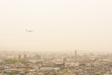 黄砂に覆われた街並みを飛ぶ飛行機