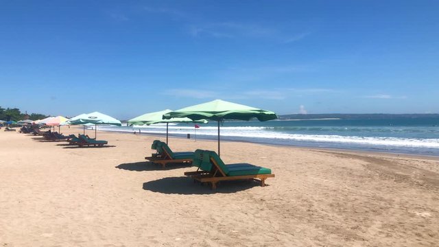 Wide sandy beach with many sunbeds and umbrellas Seminyak and Legian beach in Bali, Indonesia, 4k footage video