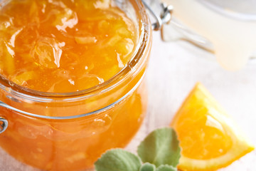 Homemade orange jam in jar on a white table. Food background Copy space