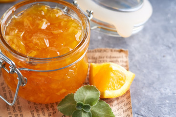 Homemade orange jam in jar on a gray table. Food background