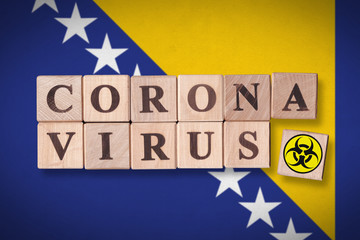 Bosnia and Herzegovina flag background and wooden blocks with letters spelling CORONAVIRUS and quarantine symbol on it. Novel Coronavirus (2019-nCoV) concept, for an outbreak occurs in BiH.