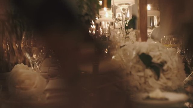 Romantic serving of table, shiny glasses in the light rays, blind date, wedding table decoration in the evening