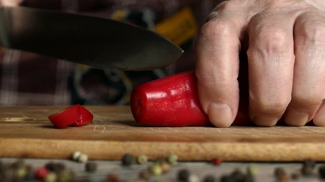 Using Knife To Cutting Ramiro Red Hot Pepper On Cutting Wooden Board. Top View. Panning Slider Shot. Close Up..