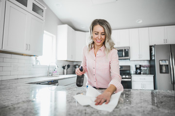 Young woman cleaning her kitchen couters with disinfectant