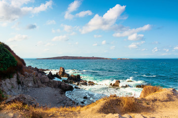 Fototapeta premium seascape with rocks and cliffs. beautiful scenery in the afternoon light. island in the distance. fluffy clouds on the evening sky. st. Ivan and st. Peter island of bulgaria in the distance
