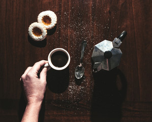 mano tiene una tazzina di caffe su un tavolo di legno con una caffettiera dei biscotti e un...
