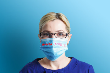 Text hantavirus, woman removes protective mask from face after infected Chinese virus. woman in medical mask on blue background. Symptoms of Hanta virus, HPS virus infection.