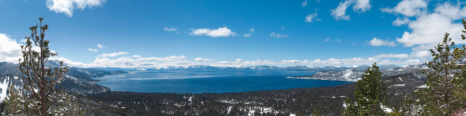 Lake Tahoe panorama with snow on the ground and view on peaks of Sierra Nevada mountains