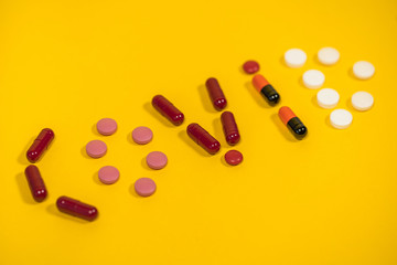 Closeup photography of word Covid 19 written on bright orange background with help of different colorful pills.