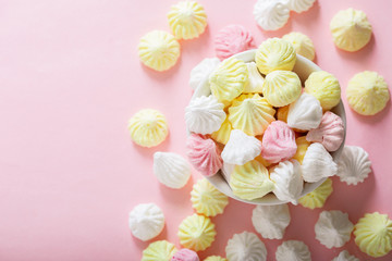 colorful meringues on pink background, top view