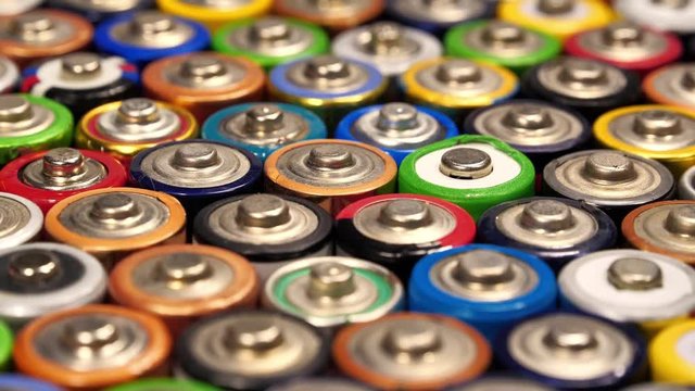 Tilt view of many multicolored used AA batteries