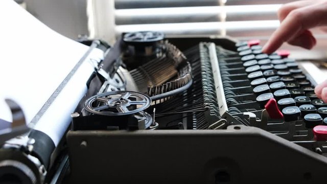 Typing on the keyboard of an old, retro typewriter.