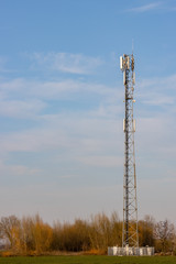 Cell phone tower in rural setting with blue sky in background