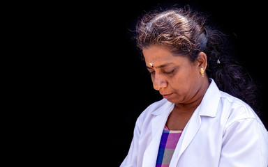 A close up picture of a doctor looking down at the uniform on a black background