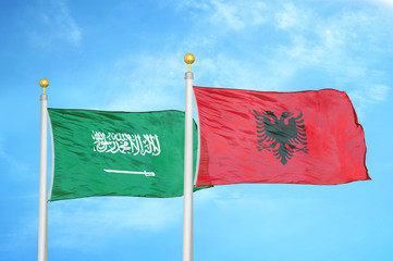 Saudi Arabia and Albania  two flags on flagpoles and blue cloudy sky
