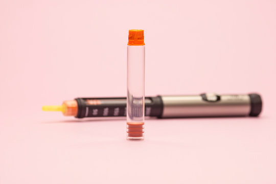injector pen for diabetes, insulin cartridge and injector on a pink background