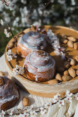 Obraz na płótnie Canvas Homemade Cinnabon Buns with Cinnamon and Cream. Tasty cakes with cream buttercream icing. Easter sweet dessert cake. Close up view. Cinnamon in blooming trees. Outdoor shooting in garden.