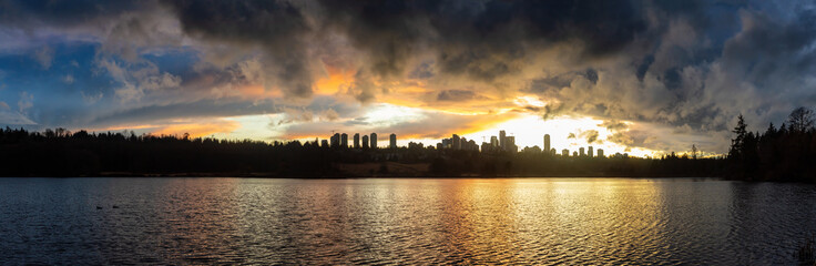 Fototapeta na wymiar Burnaby, Greater Vancouver, British Columbia, Canada. Beautiful Panoramic View of Deer Lake during a colorful and vibrant winter sunset with Metrotown Buildings in the Background. Panorama HDR