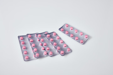 Pink pills in a blister on white acrylic table