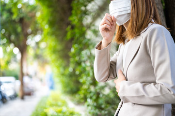 Young business woman wearing surgical mask and couging while walking in public in Coronavirus or COVID-19 spreading situation