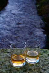 Scotch single malts or blended whisky spirits in glasses with water of river Spey on background, Scotland