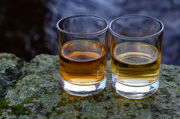 Scotch single malts or blended whisky spirits in glasses with water of river Spey on background, Scotland