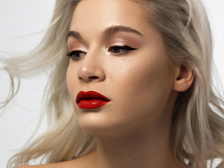 Fototapeta premium Closeup portrait of a woman with developing straight hair. Sweet tender young girl blonde. Red lipstick, transparent clean skin. Skin care natural cosmetics in the spa salon or cosmetology.