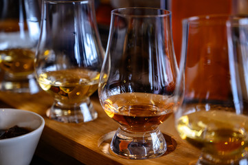 Flight of Scottish whisky, tasting glasses with variety of single malts or blended whiskey spirits on distillery tour in Scotland