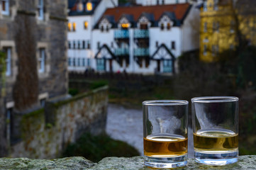 Scotch single malts or blended whisky spirits in glasses with old houses of Edinburgh on...