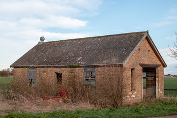 Fototapeta na wymiar Old abandoned farm building in field