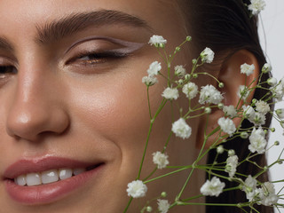 Close up portrait of a face with beautiful skin and nude makeup, eyeliner and long eyelashes, puffy...