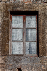 Antigua ventana de de madera vieja con cristales traslúcidos y pared de piedra