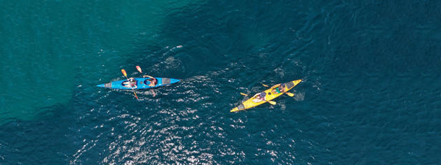 Aerial drone ultra wide photo of young couple canoeing in tropical exotic island bay